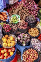 Colourful market image with a variety of fresh fruit and vegetables, including potatoes, onions and