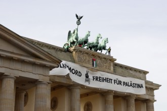 Several activists drop a banner with the inscription Never again genocide, freedom for Palestine