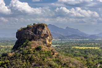 Panorama of an imposing rock formation with mountainous landscape and clouds in the background, The