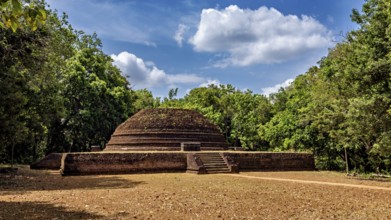 An old brick stupa surrounded by thick greenery and a cloudy sky, the temples, dagobas, and pagodas