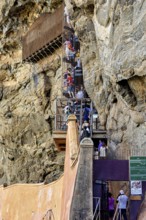 People climb a steep, rock-like structure, tourist attraction with climbing elements, tourists at