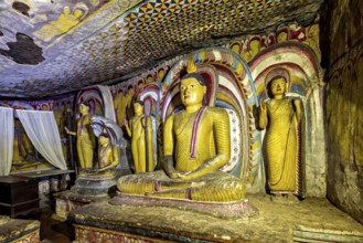 Meditative Buddha statues in a colorful cave with spiritual paintings on the walls, The cave