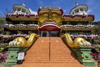 Entrance to a temple with a large golden sculpture and stone stairs decorated with ornaments, The