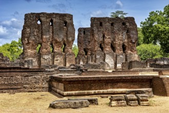 Brick ruins rising up against the sky surrounded by green foliage and crumbling architecture, The