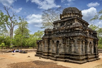 Ancient stone building amidst a ruined landscape with sky and trees, The temples of Polonnaruwa in