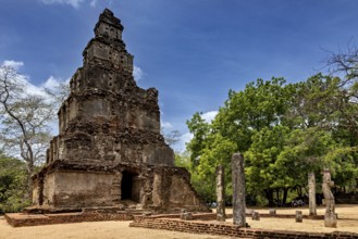 Historic ruins with a tall stone tower and trees in an open area, The temples of Polonnaruwa in Sri