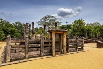 Wooden gate flanked by stone pillars on a sandy floor under a cloudy sky, The temples of