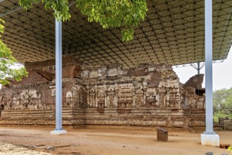 Close-up view of an ancient ruin under a protective roof with detailed wall reliefs, The temples of