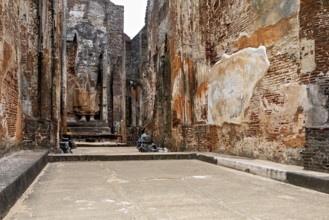 Interior view of an archaeological site with large statues and brick walls, The temples of
