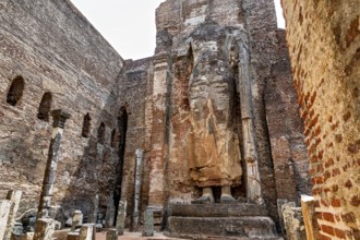 Large standing statue surrounded by ruins of old brick walls, The Temples of Polonnaruwa in Sri