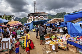 A bustling market with fruit and stalls under ominous clouds and mountain scenery, The Rurrenabaque