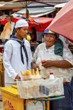 Two men at a market, one selling ice cream in colorful skittles, The Rurrenabaque market in Bolivia