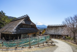 Iyashinosato open-air museum, old Japanese village with traditional houses, at the back volcano Mt.