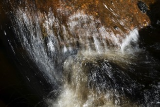 Stream flow with dark water, reflections and turbulences, long exposure, Sweden