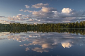 Clouds reflected on the water surface, forest lake, evening mood, at Sunne, Sweden