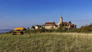 A castle on a hill with a wide meadow in the foreground and clear blue sky, The Leuchtenburg near