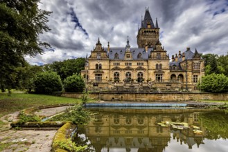 Castle with dramatic architecture reflected in a quiet pond surrounded by nature, The Hummelshain
