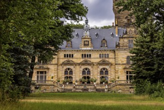 Castle hidden behind trees with a view of a green meadow, The Hummelshain hunting lodge in