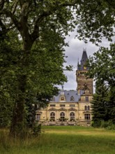A castle with a high tower, nestled in thick trees, under cloudy skies, The Hummelshain hunting
