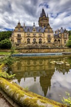 Impressive castle reflected in a quiet pond, cloudy sky above, The Hummelshain hunting lodge in