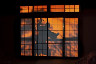 Shadow of a man, burglar with knife, assassin, ninja, on the balcony behind sliding shoji doors in