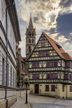 Historic alley with half-timbered house and church tower, dramatic cloud formations in the sky, the