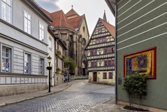 Atmospheric alley with half-timbered houses, church in the background and evening lighting, the old