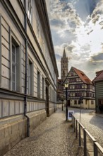Historic city center with half-timbered houses and a church in the background under a partly cloudy