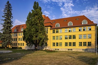 Yellow historic building with red roof, surrounded by trees and summer atmosphere, The old town of