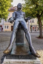 Statue of a smiling man in a square with buildings, Johann Sebastian Bach monument in the old town
