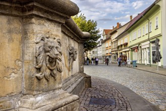 A stone lion relief in a historic old town with cobblestone streets, lion head at the fountain in