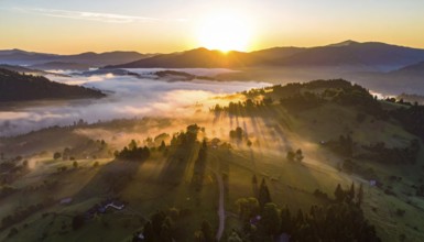 Sunrise over a fog covered village in a rural landscape, golden morning light, serene autumn