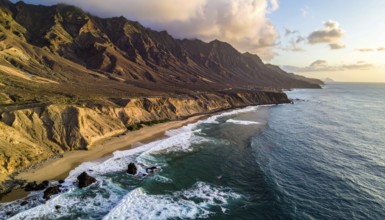 Desert landscape converges with ocean along a rugged coastal area, shore break at cliffs, blue