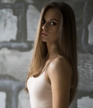 Gorgeous sexy blonde in beige body posing by a gray stone wall shot in new studio