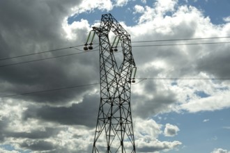 High voltage power lines against a bright blue sky with scattered clouds, Puy de Dome, Auvergne