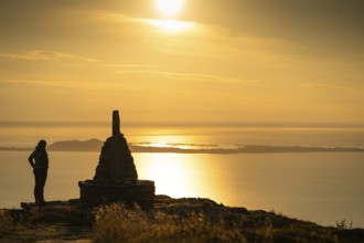 Woman standing next to cairn and looking at the sea, Rørsethornet stone staircase, with 3292 steps