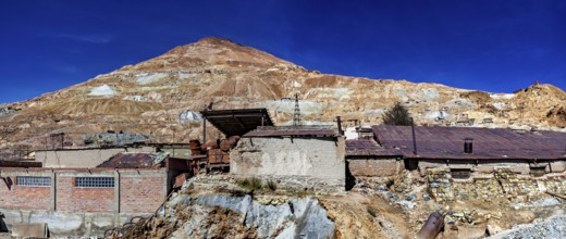Abandoned buildings on a mountainside with a rocky landscape and a clear blue sky, The silver mines