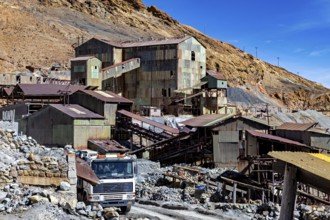 Old industrial complex with a lorry in a mountainous environment under a clear blue sky, The silver