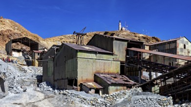 Weathered metal industrial buildings on a mountainside under a clear blue sky, The silver mines of