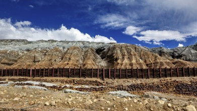 Barren mountain landscape with steep slopes under a blue sky with clouds, spoil heap of the silver