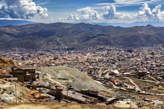 City view with surrounding mountains and numerous buildings under a cloudy sky, The silver mines of