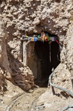 Mine entrance in a rocky landscape decorated with colourful flags, The silver mines of the Cerro