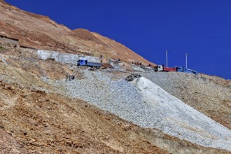 Lorries parked on the slope of a rocky mountain under a clear blue sky, The silver mines of the