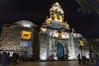 Illuminated church at night with impressive architecture and blue Tor tor, surrounded by evening