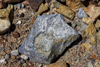 A large, grey rock on a soil of pebbles and earth, the silver ore from the Cerro Rico silver