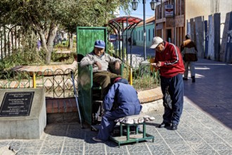 Relaxed street scene in the marketplace with men shining shoes and interacting socially, show
