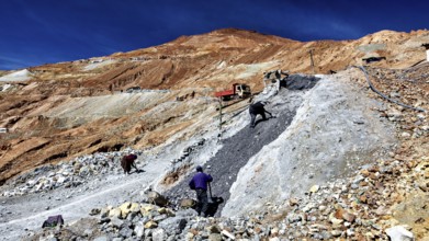 Scene of labourers working on a steep, stony slope under a blue sky, The silver mines of Potosi