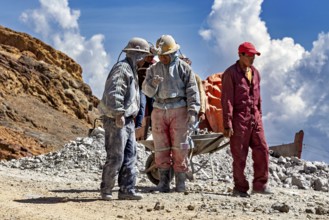 A group of miners stand and chat in a rocky landscape, The miners of the Cerro Rico silver mountain