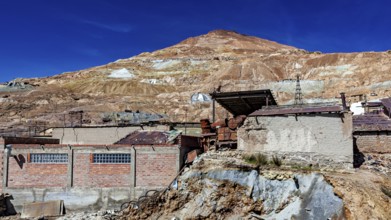 Abandoned mine buildings in front of a barren hill and clear sky, The silver mines of Potosi