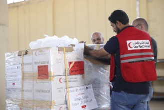 Relief workers unload boxes of medical aid provided by Qatar at Damascus International Airport,